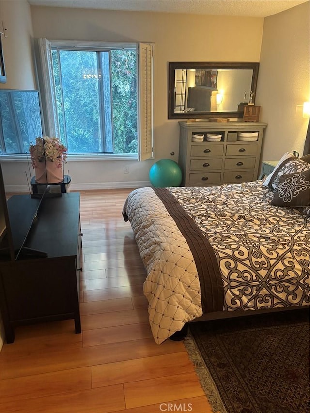 bedroom with baseboards and wood finished floors