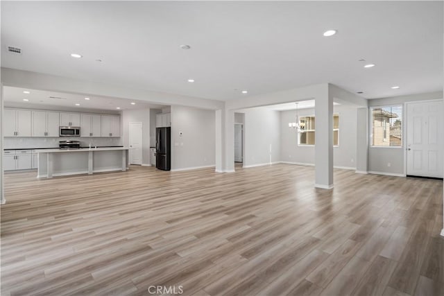 unfurnished living room featuring light wood-style floors, baseboards, visible vents, and recessed lighting