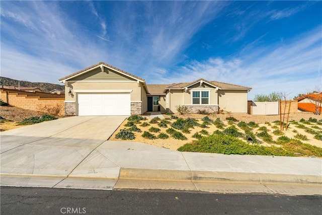 view of front facade with fence, stucco siding, concrete driveway, a garage, and stone siding