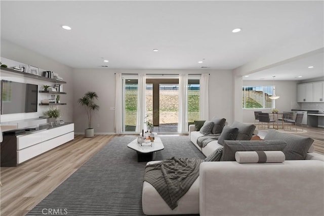 living room featuring light wood-type flooring, plenty of natural light, baseboards, and recessed lighting