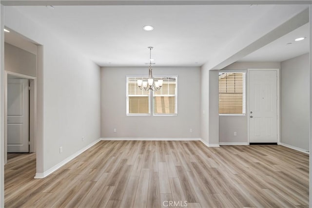 unfurnished dining area featuring light wood-style floors, baseboards, a notable chandelier, and recessed lighting