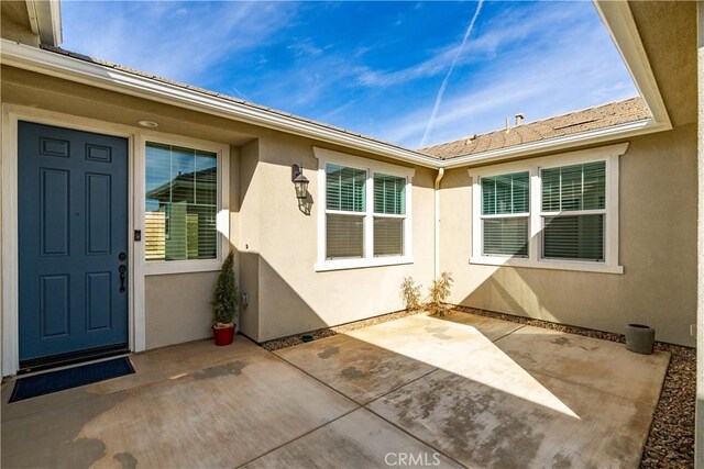 entrance to property featuring a patio and stucco siding