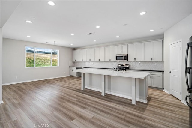 kitchen featuring appliances with stainless steel finishes, light wood-style floors, and tasteful backsplash