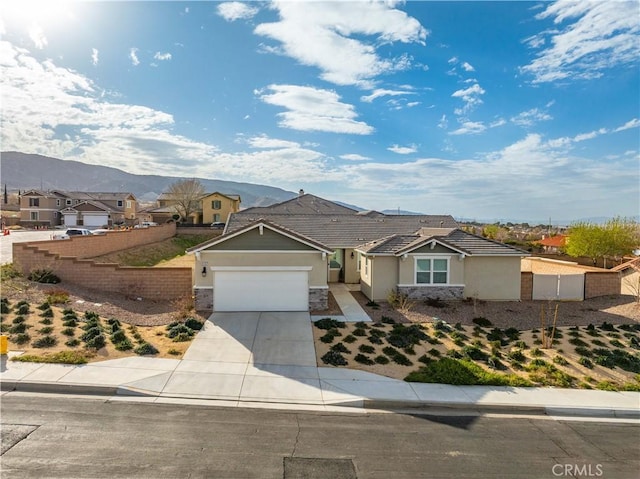 ranch-style house with an attached garage, a mountain view, fence, driveway, and stucco siding