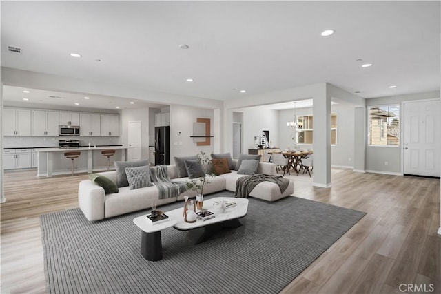 living room with recessed lighting, baseboards, visible vents, and light wood finished floors