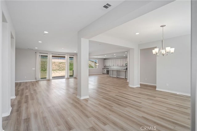 unfurnished living room with light wood-style floors, recessed lighting, visible vents, and an inviting chandelier