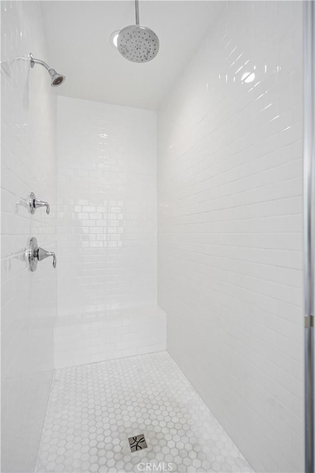 bathroom with tile patterned flooring and a tile shower