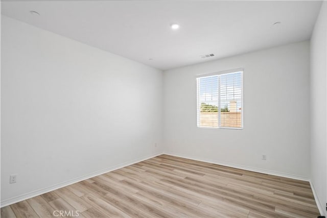 unfurnished room with visible vents, light wood-style flooring, and baseboards