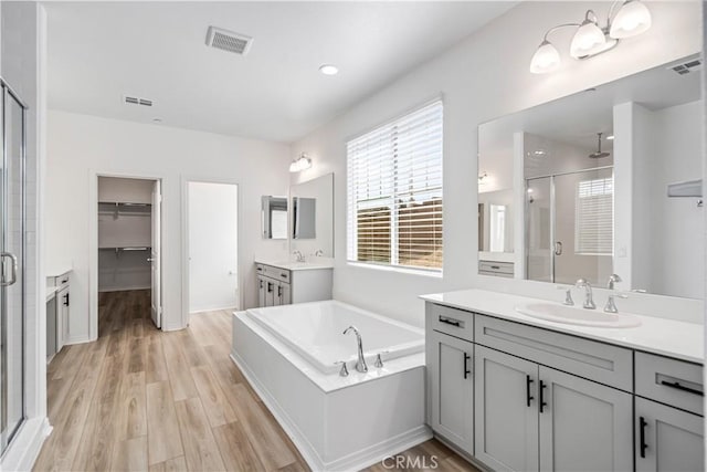 bathroom with a stall shower, a sink, and visible vents