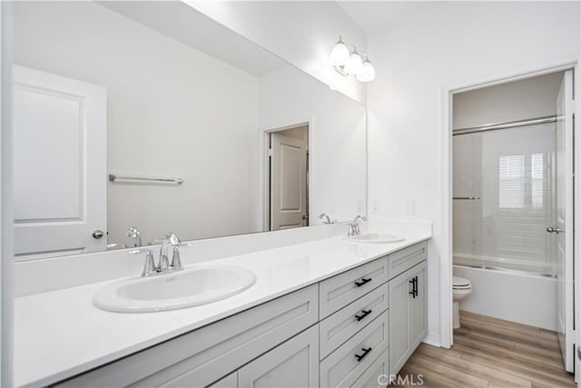 bathroom with toilet, double vanity, a sink, and wood finished floors