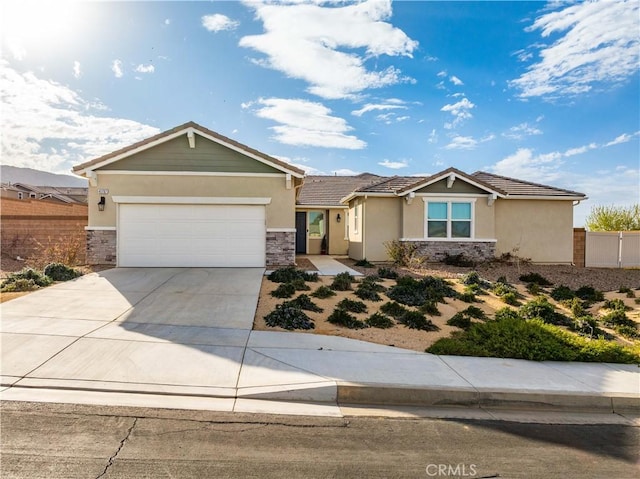 view of front of property featuring a garage, fence, stone siding, driveway, and stucco siding