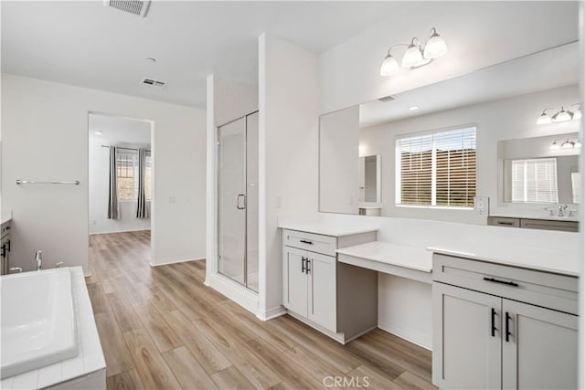 full bath featuring a bathing tub, wood finished floors, vanity, visible vents, and a shower stall