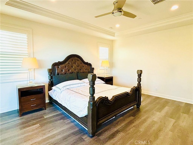 bedroom with baseboards, a raised ceiling, ornamental molding, wood finished floors, and recessed lighting