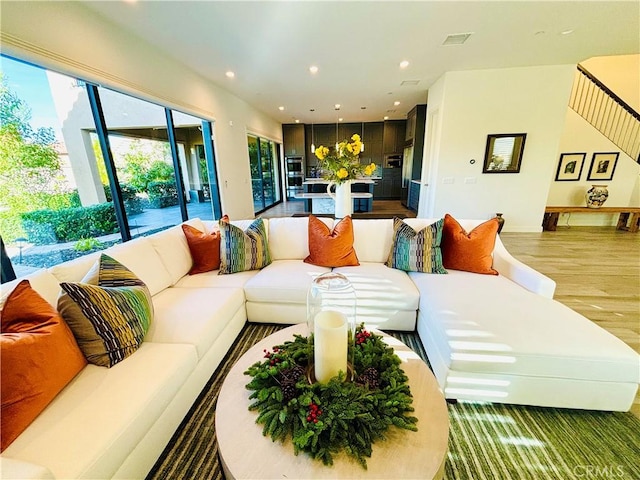 living room with stairway, wood finished floors, visible vents, and recessed lighting