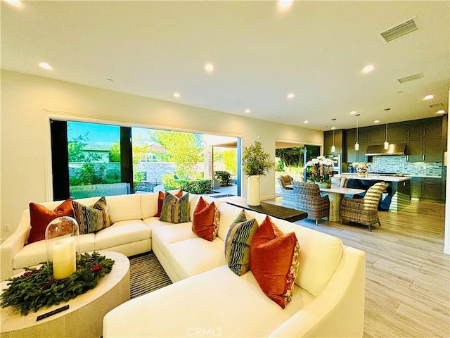 living area featuring light wood-style floors, recessed lighting, and visible vents