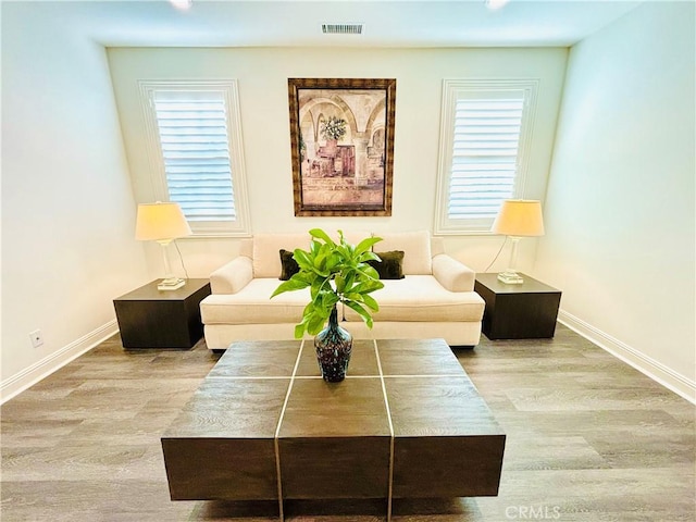 living area featuring visible vents, baseboards, and wood finished floors