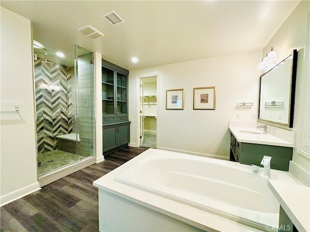 bathroom with visible vents, wood finished floors, a garden tub, vanity, and a shower stall