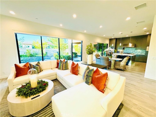 living area featuring baseboards, light wood-type flooring, visible vents, and recessed lighting