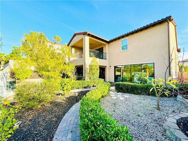 rear view of house featuring a balcony and stucco siding