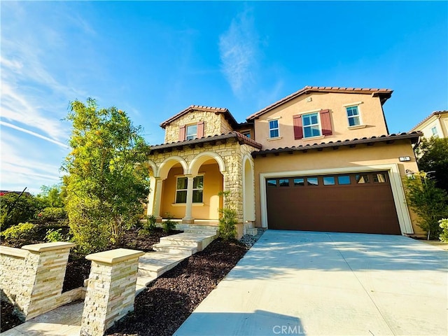 mediterranean / spanish-style house featuring a garage, concrete driveway, stone siding, covered porch, and stucco siding