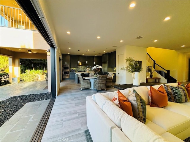 living area with recessed lighting, light wood finished floors, and stairs