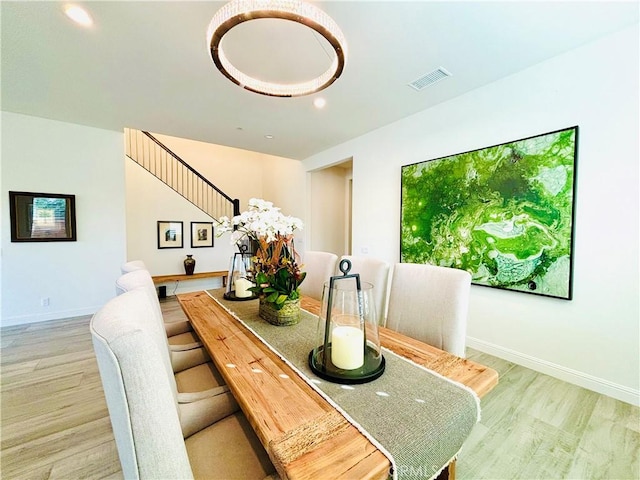 dining area with baseboards, visible vents, and wood finished floors