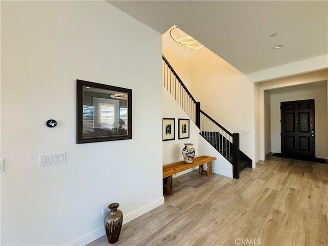 foyer with stairway, baseboards, and wood finished floors