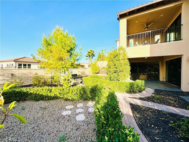 view of yard with a ceiling fan, fence, a balcony, and a patio