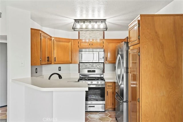 2568 Avenida Del Vis Unit 203, Corona, CA 92882 - kitchen with appliances with stainless steel finishes, a peninsula, light countertops, brown cabinets, and a sink