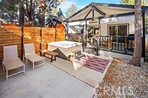 exterior space with a hot tub, fence, and a deck