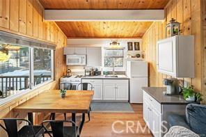 kitchen with wooden walls, white appliances, a sink, wood ceiling, and beamed ceiling