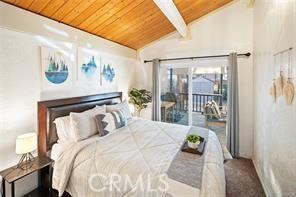 bedroom with access to exterior, wooden ceiling, carpet flooring, and vaulted ceiling with beams