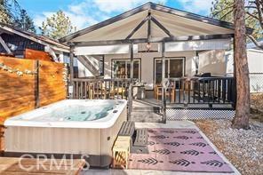 rear view of property featuring a deck, fence, and a hot tub