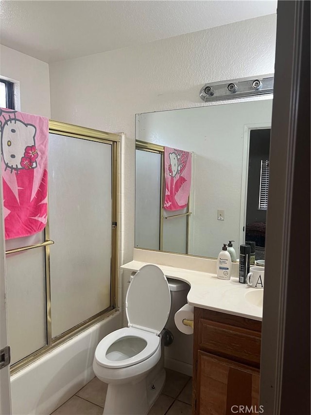 bathroom featuring tile patterned flooring, enclosed tub / shower combo, vanity, and toilet