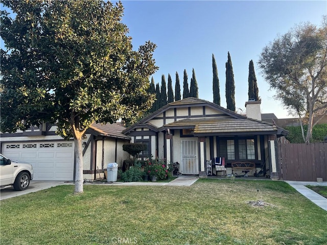 view of front of property with driveway, a garage, a chimney, fence, and a front yard