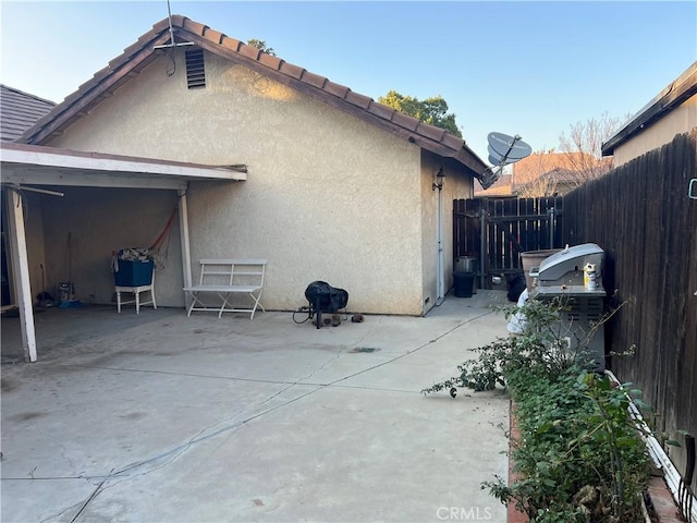 exterior space featuring a patio, a tile roof, fence, and stucco siding