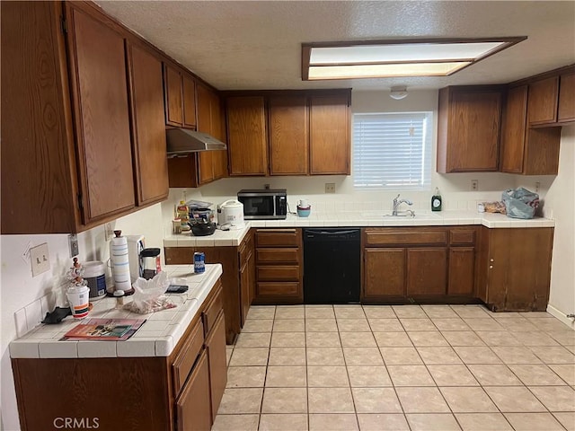 kitchen featuring tile counters, dishwasher, stainless steel microwave, under cabinet range hood, and a sink