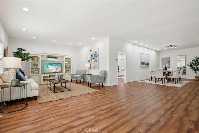 living area featuring baseboards, wood finished floors, and recessed lighting