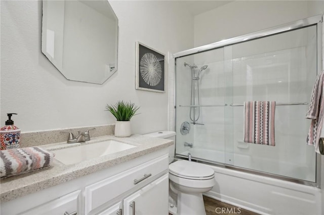 bathroom with toilet, combined bath / shower with glass door, and vanity