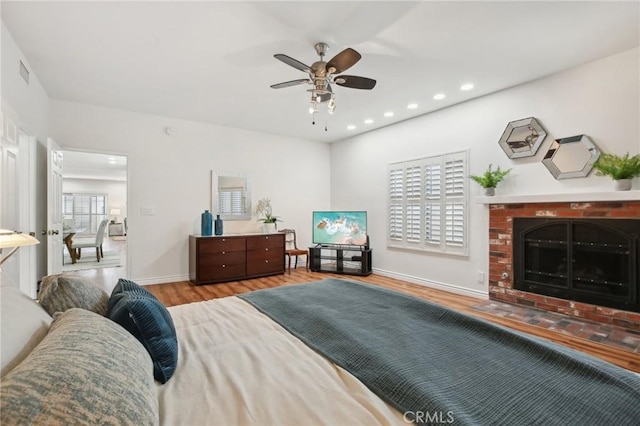 bedroom with recessed lighting, a fireplace, wood finished floors, visible vents, and baseboards