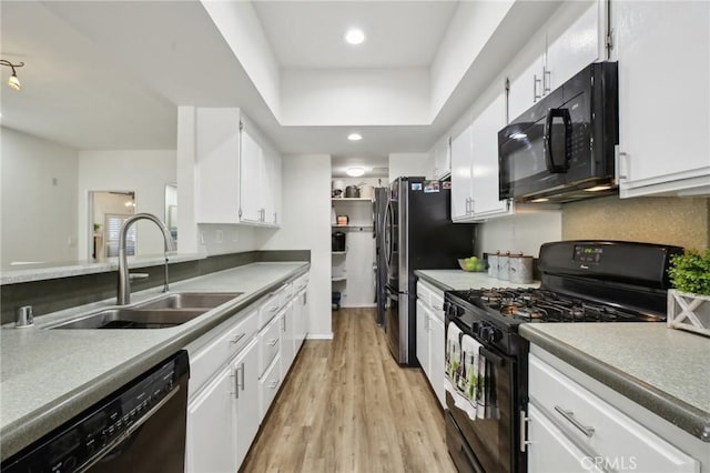 kitchen featuring white cabinets, light wood-style flooring, black appliances, a sink, and recessed lighting