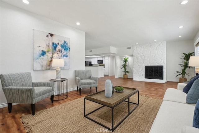 living room with a fireplace, visible vents, wood finished floors, and recessed lighting