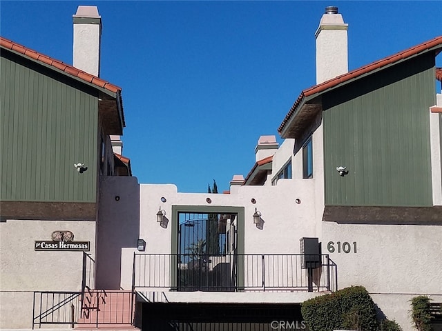 rear view of house with a chimney and stucco siding