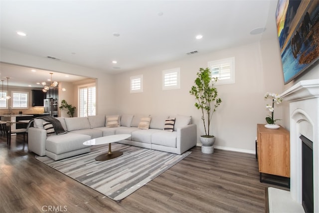 living room featuring wood finished floors, visible vents, and a notable chandelier