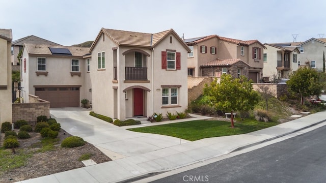 view of front of house with a tile roof, stucco siding, a balcony, a garage, and driveway