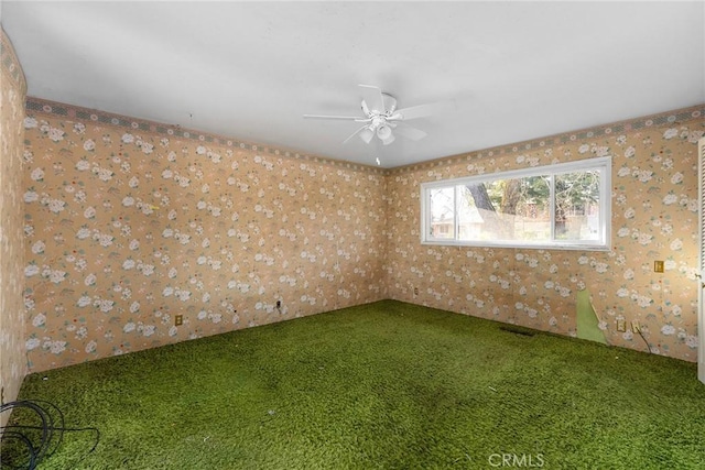 carpeted spare room featuring a ceiling fan and wallpapered walls