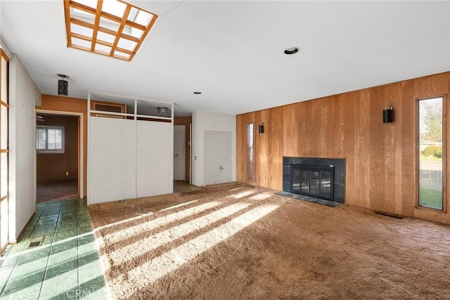 unfurnished living room with a fireplace with flush hearth, plenty of natural light, and wooden walls