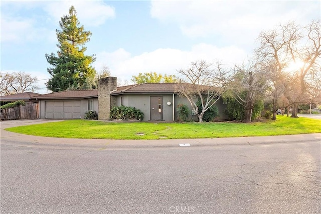 view of front facade featuring a garage, concrete driveway, a chimney, fence, and a front lawn