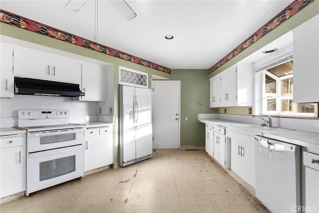 kitchen featuring under cabinet range hood, white appliances, a sink, white cabinets, and light floors