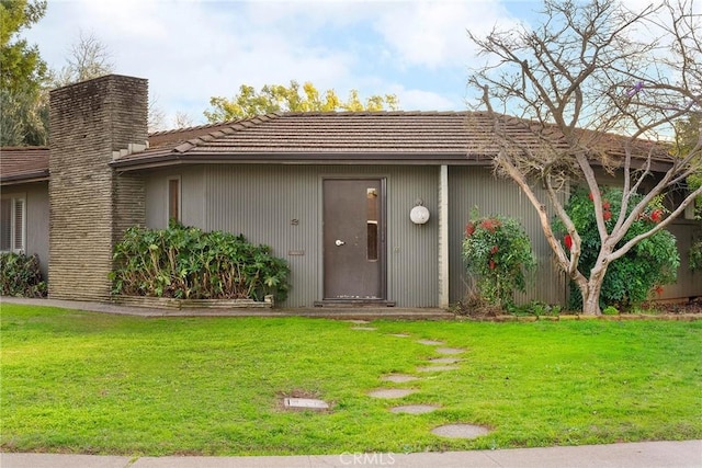 exterior space featuring a tiled roof and a lawn